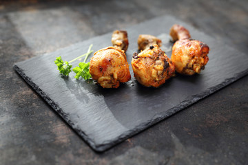 Apetyczne nóżki z kurczaka ze złocistą, chrupiącą skórką na ciemnym kamiennym talerzu. © foodandcook