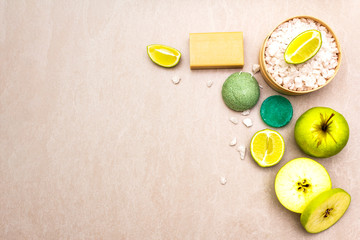 Spa concept, natural ingredients. Bath towel, sea salt with lime, apple, olive and mint soap, sponge. On a stone background, top view