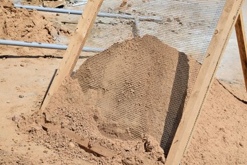 sifting sand through a grid at a construction site