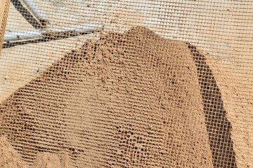 sifting sand through a grid at a construction site
