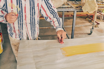 Artist using paint brush for making artificial wood texture.