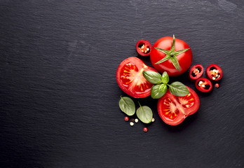 fresh  tomatoes with pepper and basil on black  stone background