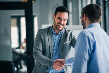 Portrait of cheerful young manager handshake with new employee. - obrazy, fototapety, plakaty