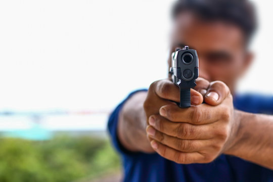 The man with the blurred face holds the gun.