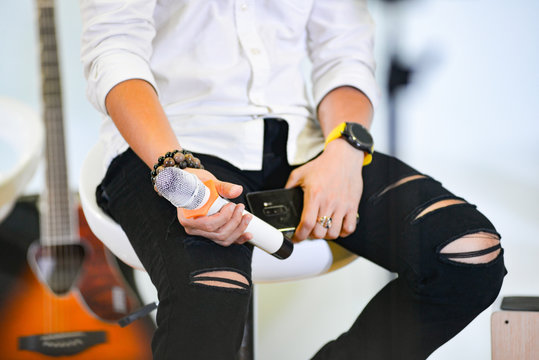 An unidentified young Asian man in one hand wearing a watch and one hand holding a wireless microphone, he wore a white shirt. He is a singer, mc or celebrity in a talkshow. Photos without face