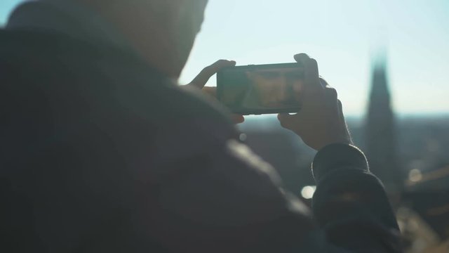 Male tourist taking shot of old european city center, aerial view from skydeck