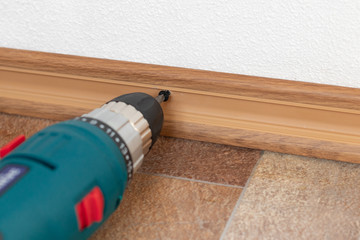 Installation of plastic floor plinth. Interior details.