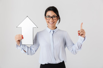 Photo of businesslike office woman wearing eyeglasses holding blank arrow pointer, isolated over white background