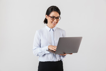 Portrait of businesslike woman wearing eyeglasses holding silver laptop in the office, isolated over white background - obrazy, fototapety, plakaty