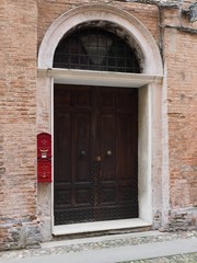 Ferrara, Italy. Old wooden door and red mailbox.