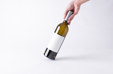Hand holding a wine bottle for mock-up. Blank Label on a gray background.
