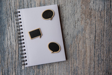Notebook covered in speech bubbles, taken on a wooden background with copy space