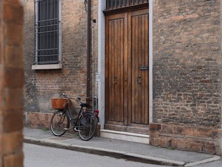 Fototapeta na wymiar Ferrara, Italy. Historic centre, street and facade with bike.