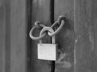 Door closed by a lock, detail. Black and white photo.