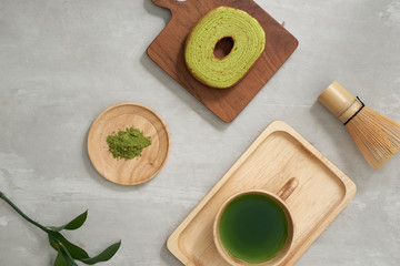 Fototapeta na wymiar Green tea matcha in a wooden cup with German cake on the brown mat close-up