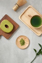 Fototapeta na wymiar Green tea matcha in a wooden cup with German cake on the brown mat close-up