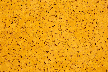 Dark yellow colored rubber floor background texture. Shock absorbent flooring for gyms, playgrounds, sports and running tracks
