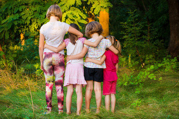 Back view of sad children stand in hug together in summer day