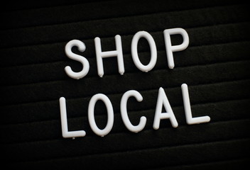 The words Shop Local in white plastic letters on a notice board
