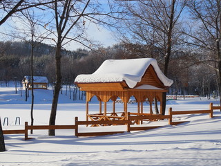 beautiful winter landscape with a wooden pergola covered with a thick layer of snow on a Sunny frosty day