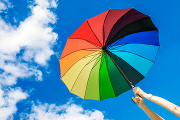 Multi-colored umbrella on the sky background.girl holding an umbrella