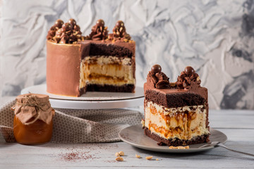 A big chocolate cake with peanuts on the white wooden background