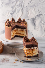 A big chocolate cake with peanuts on the white wooden background
