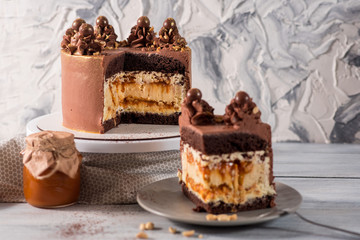 A big chocolate cake with peanuts on the white wooden background