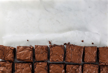 Chocolate brownie on paper on marble top view flat lay text space on top
