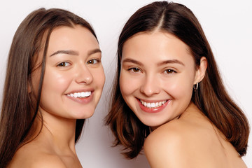 make up and skin care concept - Portrait of a two beautiful sexy young women - Isolated on white. Two smiling attractive girl friends