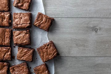 Schokoladenbrownie auf Papier auf dunkelgrauer Basis Draufsicht flach gelegt © graham