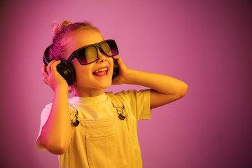 Neon portrait of young girl with headphones enjoying music. Lifestyle of young people, human emotions, childhood, happiness concept.