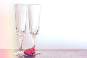 Two champagne glasses and two chocolate heart candies with copy space and vintage effect