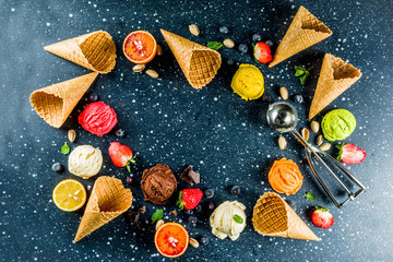 Colorful fruit and berry, nut, chocolate and vanilla ice cream, with waffle ice-cream cones, with fresh fruit and berries, top view copy space dark blue background