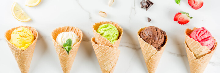 Colorful fruit and berry, nut, chocolate and vanilla ice cream, with waffle ice-cream cones, with fresh fruit and berries, top view copy space white marble background banner
