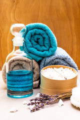 Obraz na płótnie Canvas Spa concept, natural ingredients. Bath towels, sea salt with lavender, shower gel, brush. On a stone and wooden background