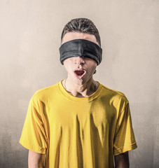 ragazzo con maglietta gialla ed benda nera sugli occhi