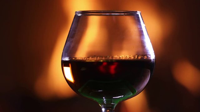 A glass of brandy against the burning fireplace indoors