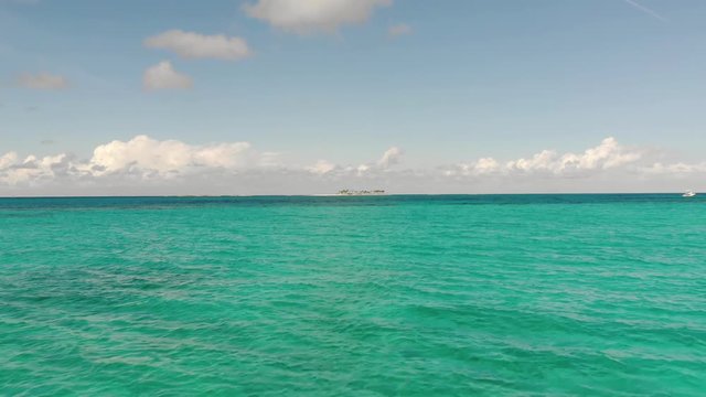 Rising up over beautiful blue sea in the Bahamas, Caribbean towards a small deserted island, pirate island, rose island, Aerial view