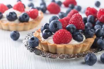 Fototapeta premium Dessert tarts with raspberries and blueberries on a wooden table.