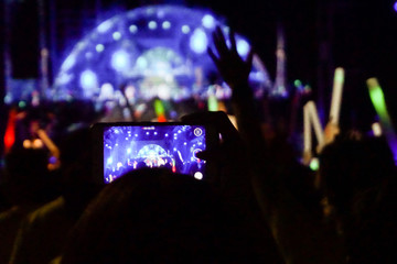 Fototapeta na wymiar Women are taking pictures concert with smartphones, Crowd at concert.
