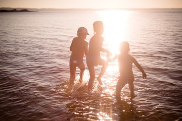 Silhouettes of children playing in the sea at sunset