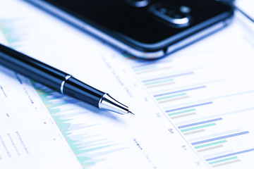 pen,cellphone and business statistics on wooden table