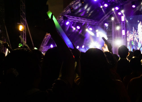 Silhouettes of crowd at concert, People with hands up.