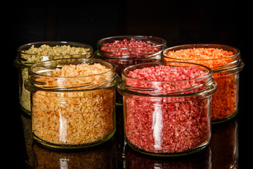closeup small glass jars filled with different colors sea salt