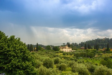 Fototapeta na wymiar Beautiful view of the Tuscany fields from the top of the hill at Boboli Garden. Rainy cloudy clouds over the beautiful Tuscan landscape. Florence, Italy.