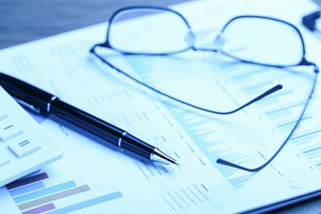 pen,glasses,calculator and business statistics on wooden table