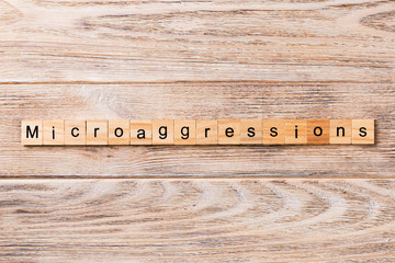 Microaggressions word written on wood block. Microaggressions text on wooden table for your desing,...