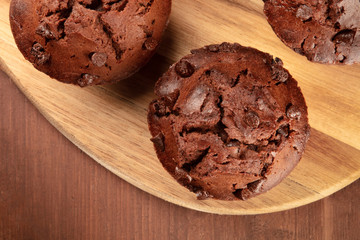 An overhead closeup photo of chocolate muffins on a dark rustic wooden background with copy space