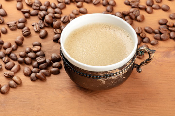 Coffee in a vintage cup with coffee beans on a dark rustic wooden background